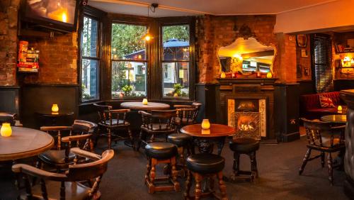 um restaurante com mesas e cadeiras e uma lareira em The Foresters Arms em Kingston upon Thames