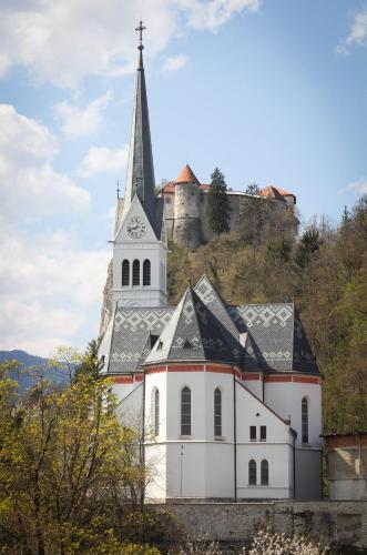 a white church with a steeple and a castle at N&J Villa Swan Bled in Bled