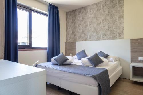 a bedroom with a white bed with blue pillows at Arco Smart Hotel in Arco
