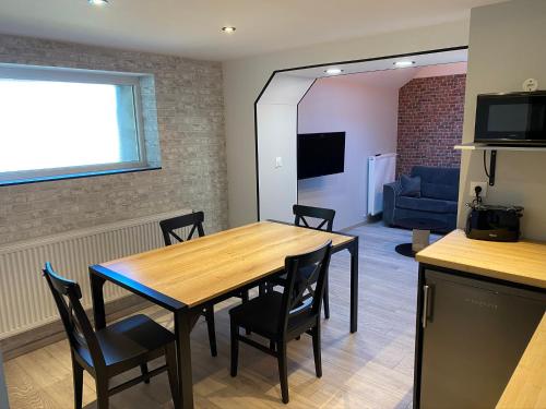 a dining room with a table and chairs and a couch at Logements équipés à Onnaing avec espace Balneo en OPTION proche Toyota, autoroute et Valenciennes in Onnaing