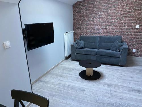 a living room with a couch and a table at Logements équipés à Onnaing avec espace Balneo en OPTION proche Toyota, autoroute et Valenciennes in Onnaing