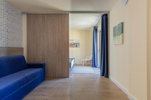 a living room with a blue couch and a hallway at Arco Smart Hotel in Arco