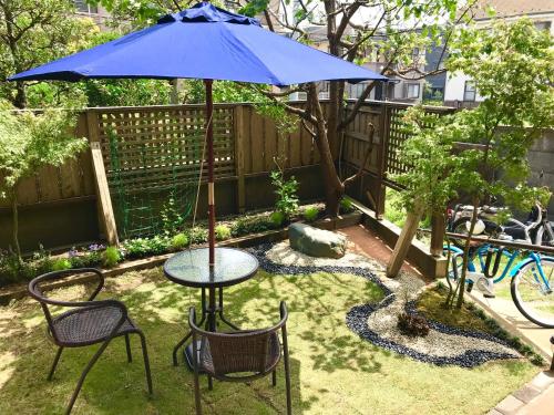 un patio con mesa, sillas y sombrilla en Guest House Kamakura Zen-ji, en Kamakura