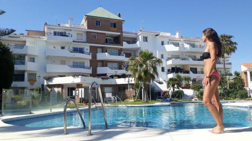 a woman standing in a swimming pool next to a building at Apartment Riviera del Sol - Seaview in Mijas Costa