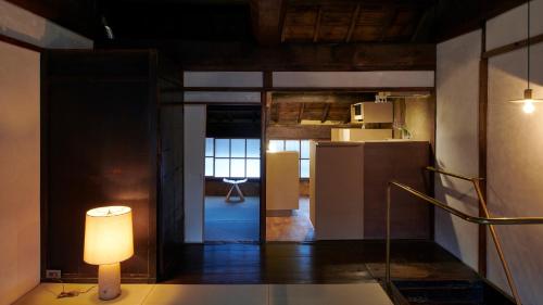a living room with a lamp and a kitchen at 宿一灯 Guest House HITOTOMORI in Mitsugarasuchō