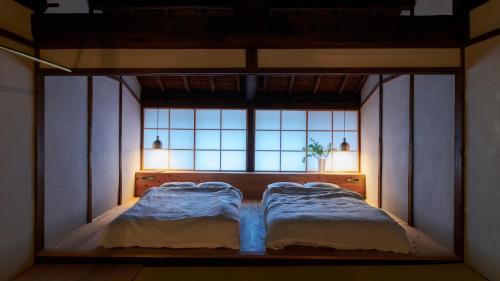 a bedroom with two beds in front of a window at 宿一灯 Guest House HITOTOMORI in Mitsugarasuchō