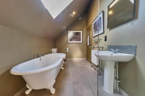 baño con bañera grande y lavamanos en The Westleton Crown, en Westleton