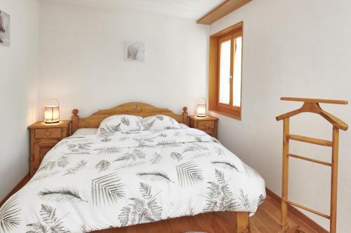 1 dormitorio con 1 cama con edredón blanco y 2 lámparas en Magnifique appartement aux Diablerets avec vue imprenable, en Les Diablerets