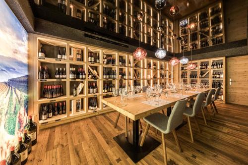 a dining room with a table with chairs and wine bottles at DAS GERSTL Alpine Retreat in Malles Venosta