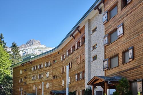 a large brick building with a mountain in the background at Magnifique appartement aux Diablerets avec vue imprenable in Les Diablerets