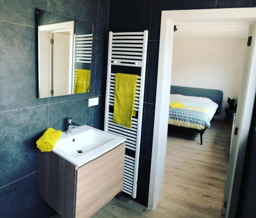 a bathroom with a sink and a mirror and a bed at Die huis 14-Een oase van rust tussen polders en kust in Ostend