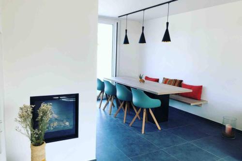 a dining room with a table and blue chairs at Die huis 14-Een oase van rust tussen polders en kust in Ostend