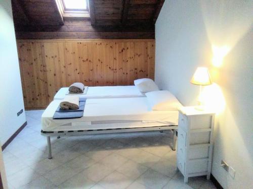 1 dormitorio con 2 camas y mesita de noche con lámpara en lago dorato, en Dervio