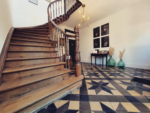 a wooden staircase in a room with a checkered floor at Sojolidays - Appartements d'hôtes sur la Route des Vins d'Alsace in Rorschwihr