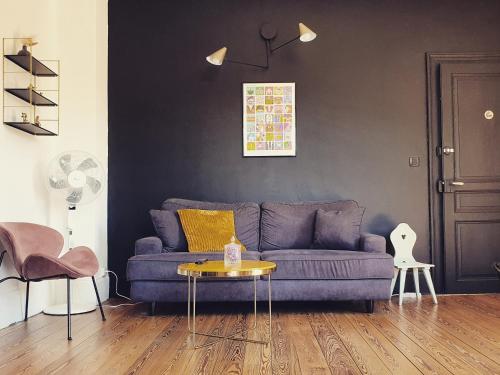 a living room with a purple couch and a table at Sojolidays - Appartements d'hôtes sur la Route des Vins d'Alsace in Rorschwihr