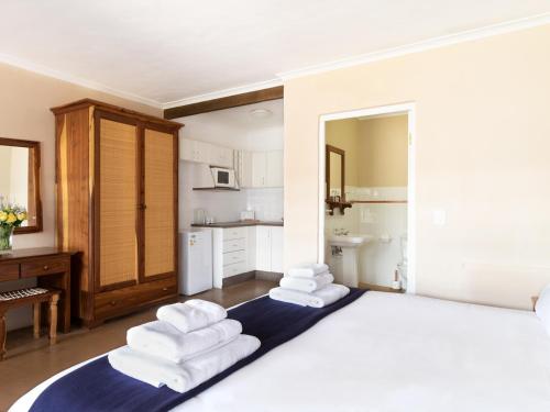 a bedroom with a large bed with towels on it at Ongegund Lodge in Somerset West