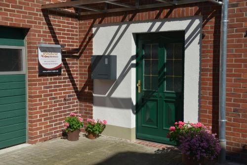 a green door on a brick building with flowers at Gästehaus Rothert in Bramsche