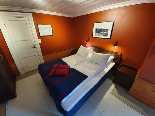 a small bed in a room with an orange wall at Vertshuset Røros in Røros