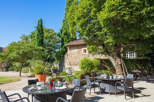 a patio with tables and chairs and a building at Le Pré du Moulin - Maison Alonso - Hôtel & Restaurant in Sérignan-du-Comtat