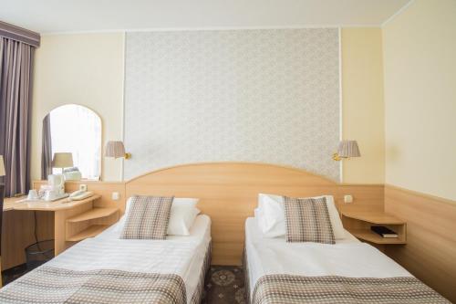 a hotel room with two beds and a mirror at Hotel Orion Várkert in Budapest