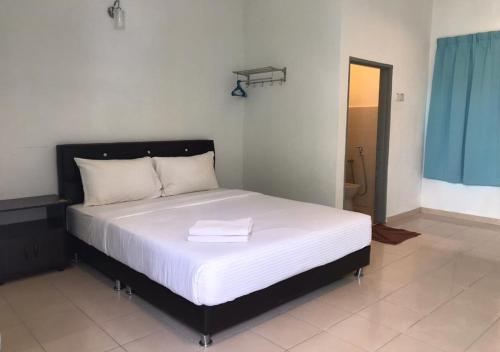 Un dormitorio con una cama grande con un edredón blanco. en Alpha Motel, en Pantai Cenang