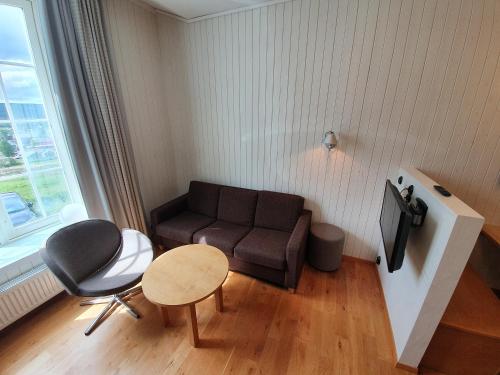 a living room with a couch and a table and a tv at Vertshuset Røros in Røros