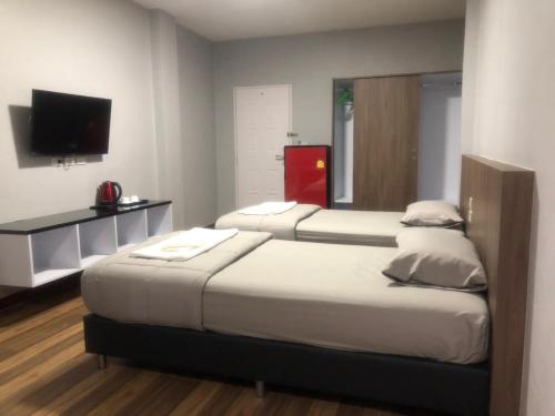 2 Betten in einem Zimmer mit einem TV und einem Zimmer mit 2 Betten in der Unterkunft Chai Style Mansion in Ban Khlong Bang Bon