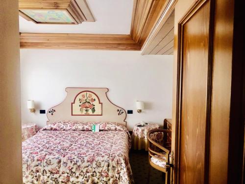 a bedroom with a bed with a floral bedspread at Hotel Alla Posta - Famiglia Pra dal 1866 a Caprile in Alleghe