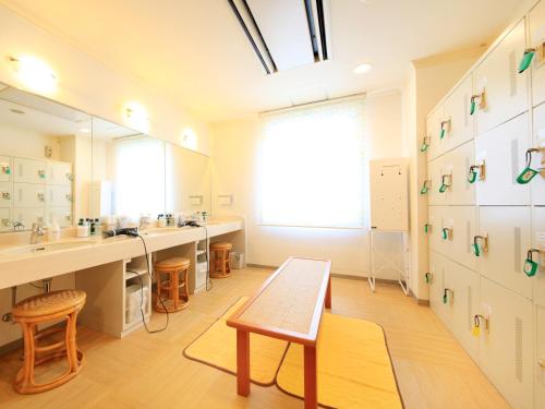 a bathroom with two sinks and a bench in it at Hotel Premium Green Sovereign in Sendai