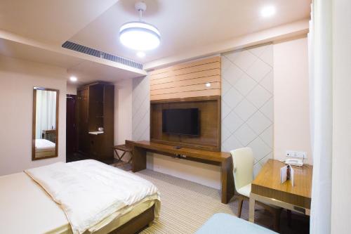 a bedroom with a bed and a desk with a television at Hotel Fun Residency by Antra Group in Ahmedabad