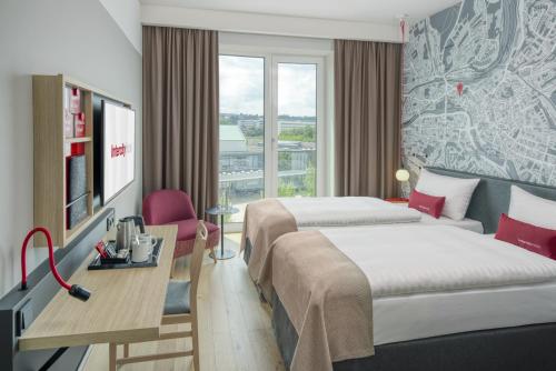 ein Hotelzimmer mit 2 Betten und einem Schreibtisch in der Unterkunft IntercityHotel Saarbrücken in Saarbrücken