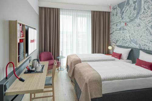 a hotel room with two beds and a desk at IntercityHotel Saarbrücken in Saarbrücken