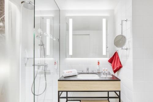 a white bathroom with a sink and a shower at IntercityHotel Saarbrücken in Saarbrücken