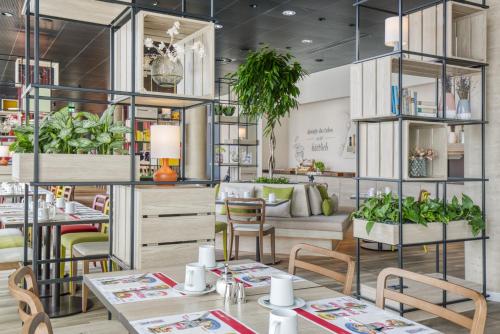 a restaurant with tables and chairs and potted plants at IntercityHotel Saarbrücken in Saarbrücken