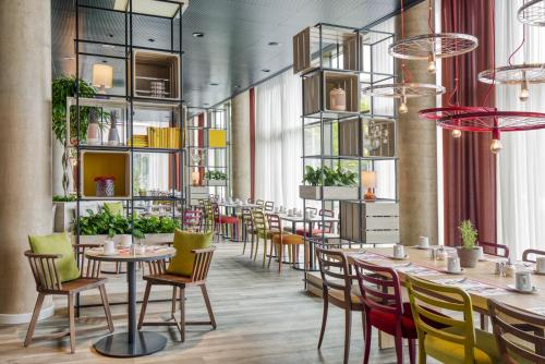 a restaurant with tables and chairs and plants at IntercityHotel Saarbrücken in Saarbrücken