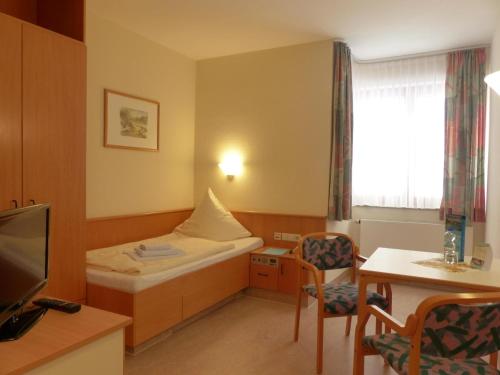 a small room with a bed and a table and a window at Rehaklinik Thermalbad Wiesenbad in Thermalbad Wiesenbad