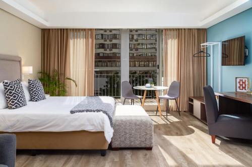 a bedroom with a bed and a table and chairs at WINK Aparthotel Foreshore in Cape Town