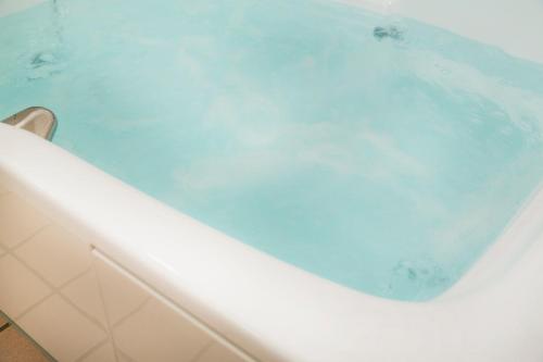 HOTEL LUNA Izumiotsu (Adult Only) في Shōki: حوض استحمام مملوء بالماء الأزرق في الحمام