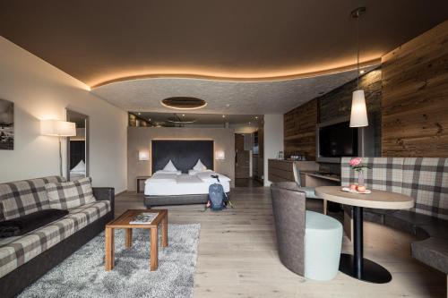 a hotel room with a bed and a couch at DAS GERSTL Alpine Retreat in Malles Venosta