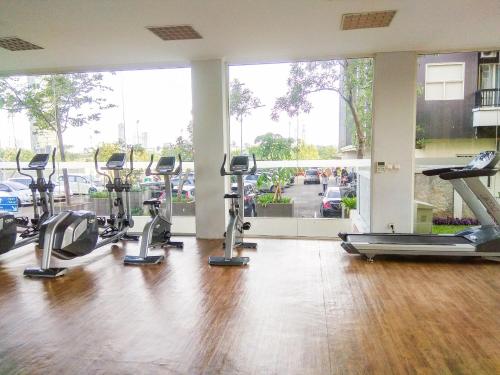 a gym with several treadmills and elliptical machines at Tidy 2BR Apartment at Silkwood Residences near BINUS By Travelio in Tangerang