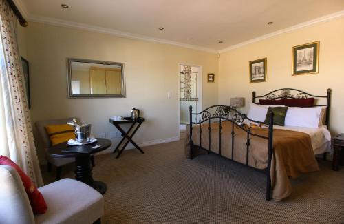 a bedroom with a bed and a chair at Port House in Bloubergstrand