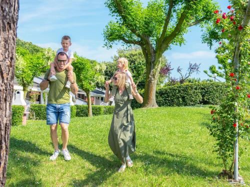 a man and two children are standing in the grass at Portofelice Camping Village in Eraclea Mare