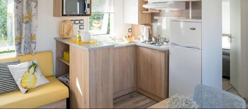 a small kitchen with a yellow couch in a tiny kitchen at Camping la Haie Penée **** in Saint-Quentin-en-Tourmont