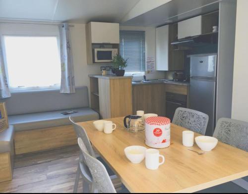 a kitchen with a wooden table with white cups on it at Camping la Haie Penée **** in Saint-Quentin-en-Tourmont