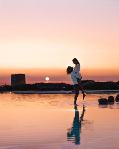 a woman is playing on the beach at sunset at Hotel Relax Torreruja Thalasso & Spa in Isola Rossa