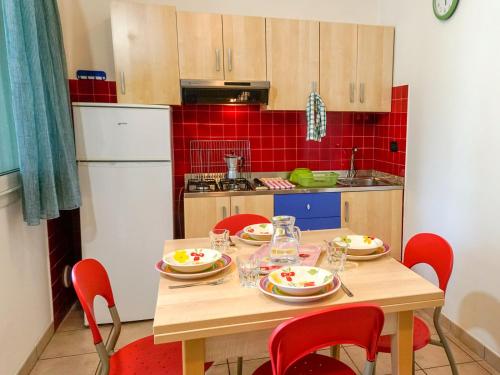 a kitchen with a wooden table with red chairs at Portofelice Camping Village in Eraclea Mare