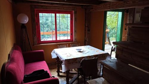un soggiorno con tavolo e finestra rossa di AGROTURYSTYKA TEOSIOWO a Pobiedna