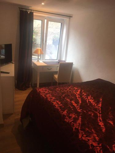a bedroom with a bed and a desk and a window at Ferienwohnungen Blume am Schloßberg in Bad Berka