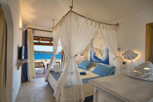 a bedroom with a canopy bed with a view of the ocean at Hotel Relax Torreruja Thalasso & Spa in Isola Rossa