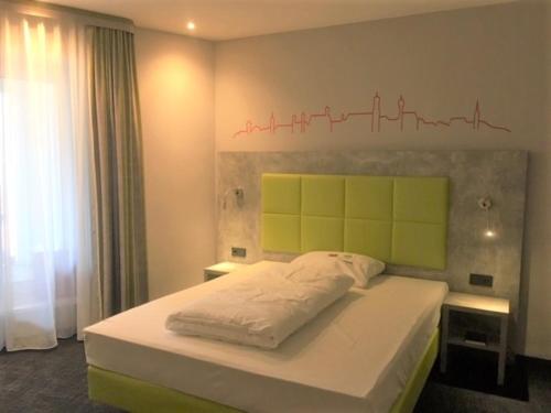a bedroom with a bed with a green headboard at SleepySleepy Hotel Dillingen in Dillingen an der Donau